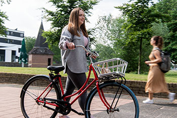 Female student pushing a bicycle through campus
