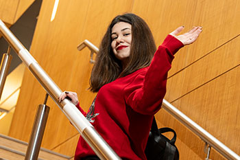 Female student on staircase waving