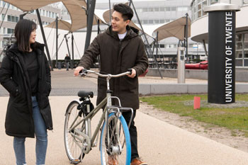 Student pushing a bicycle through campus