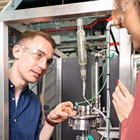 Male and female student working in lab wearing safety goggles